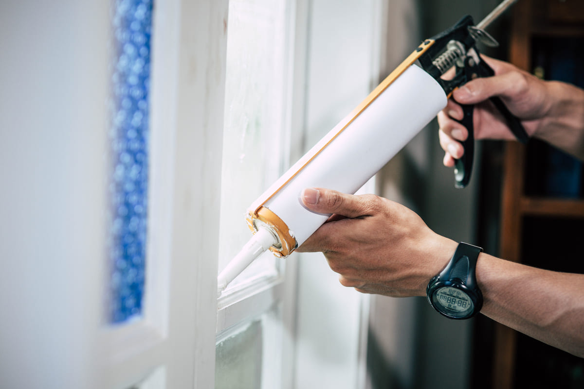 Applying weather-resistant caulk to window frames for Pennsylvania winter preparation